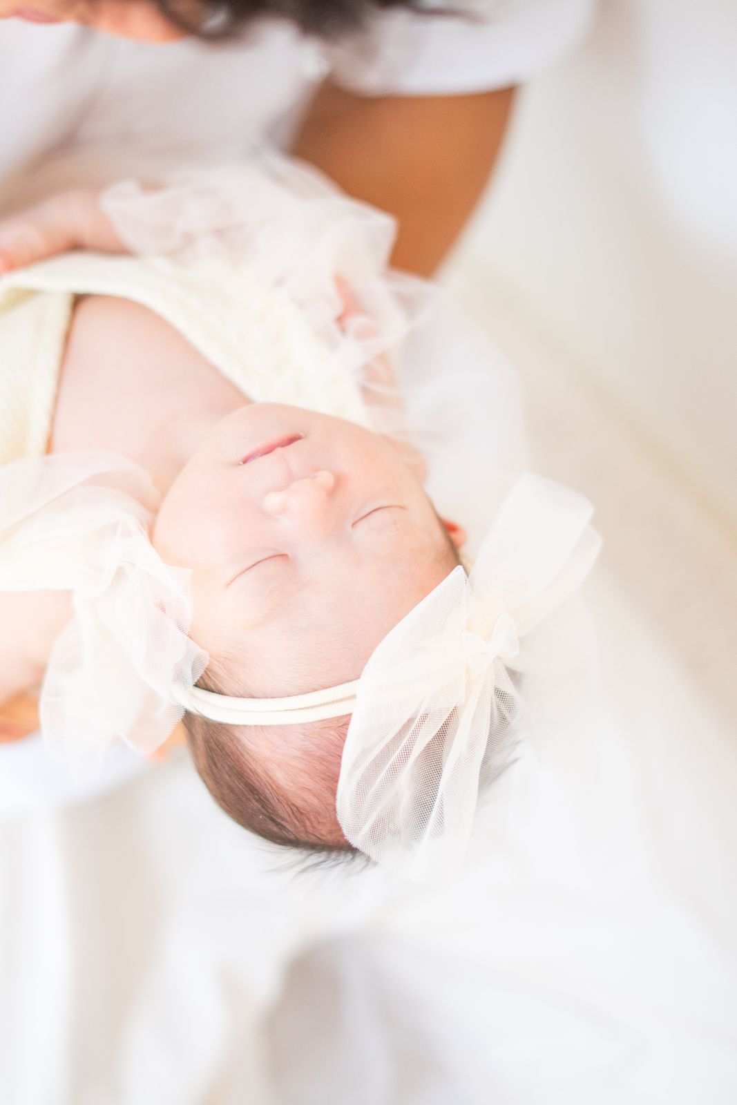 リボンを付けて眠る新生児の写真