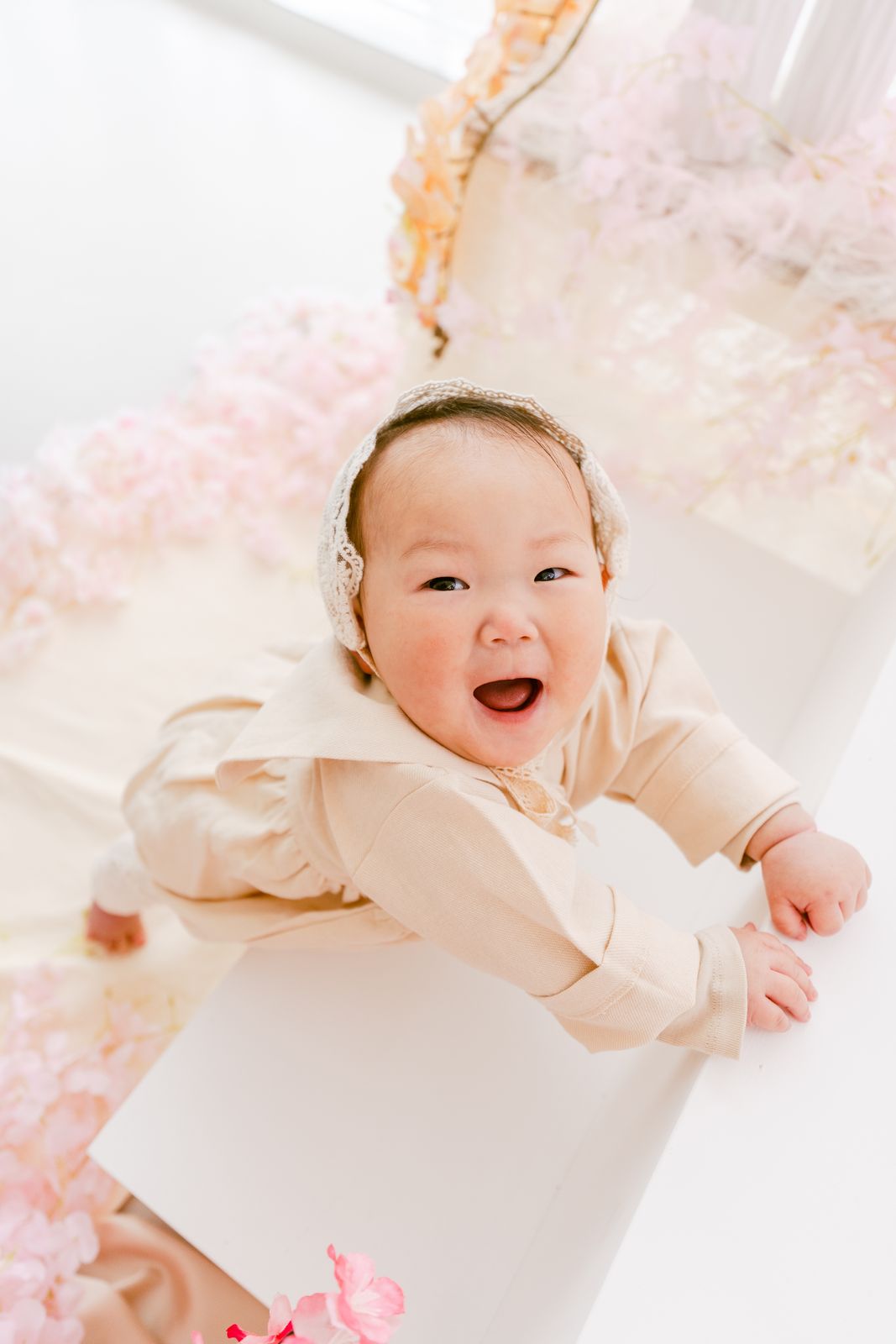 桜の装飾の中で笑う赤ちゃんの写真