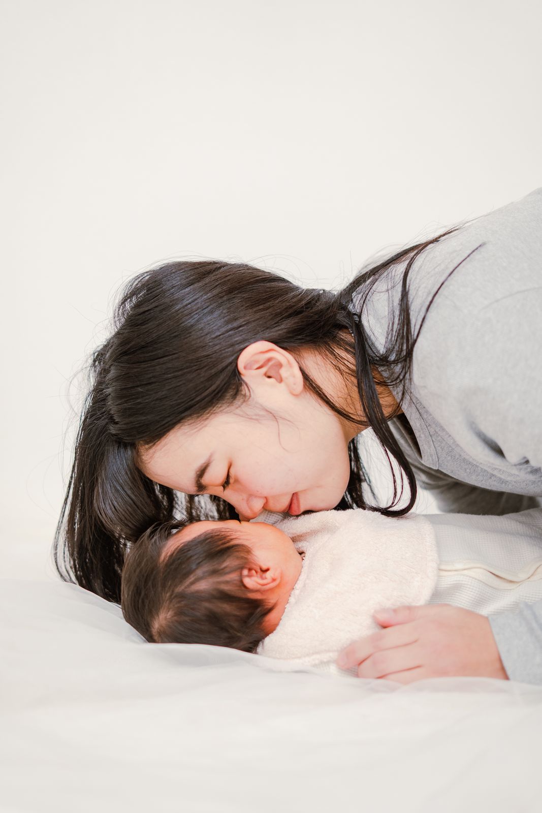 新生児にそっとキスをするお母さんの写真