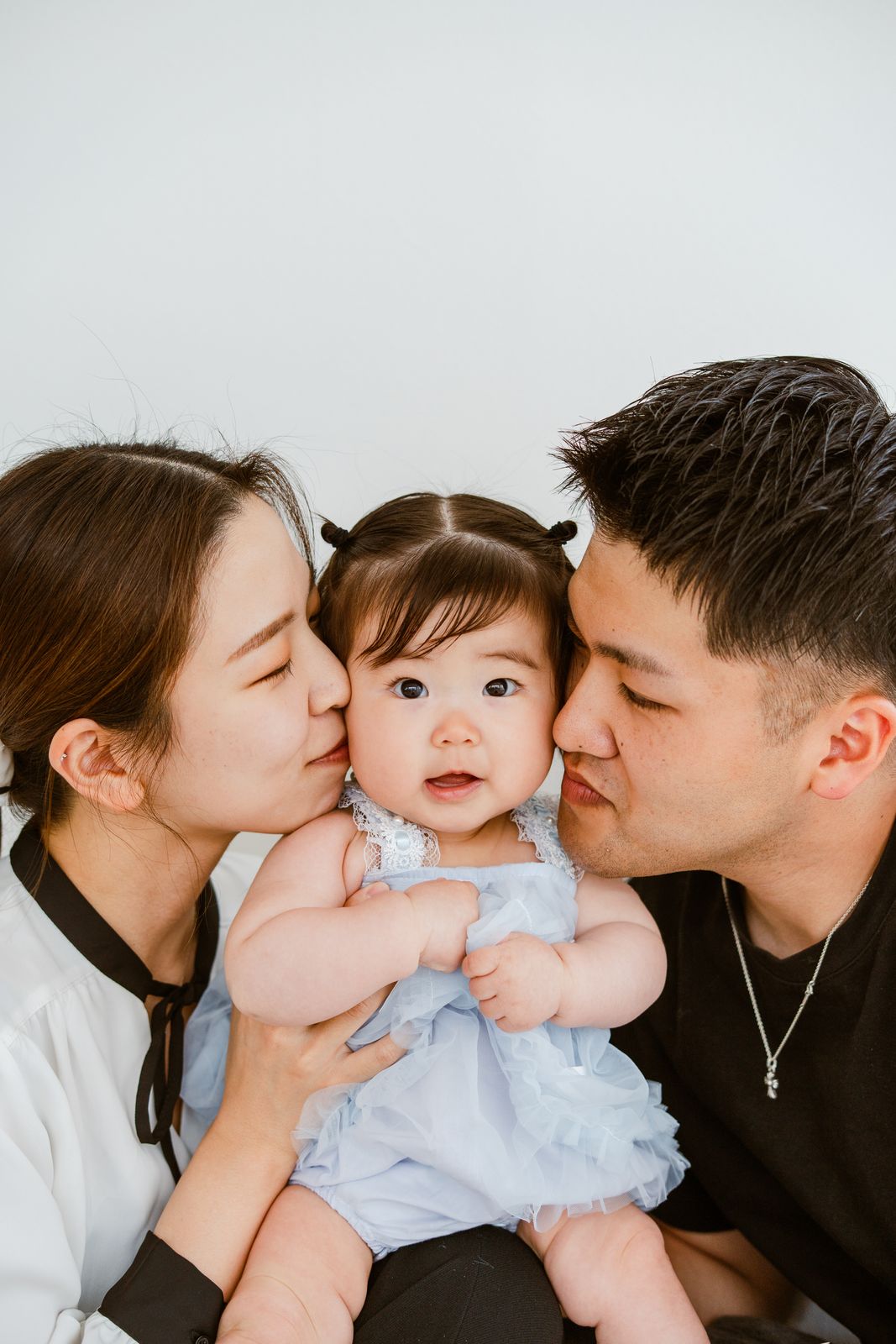 赤ちゃんに頬を寄せるご両親の写真