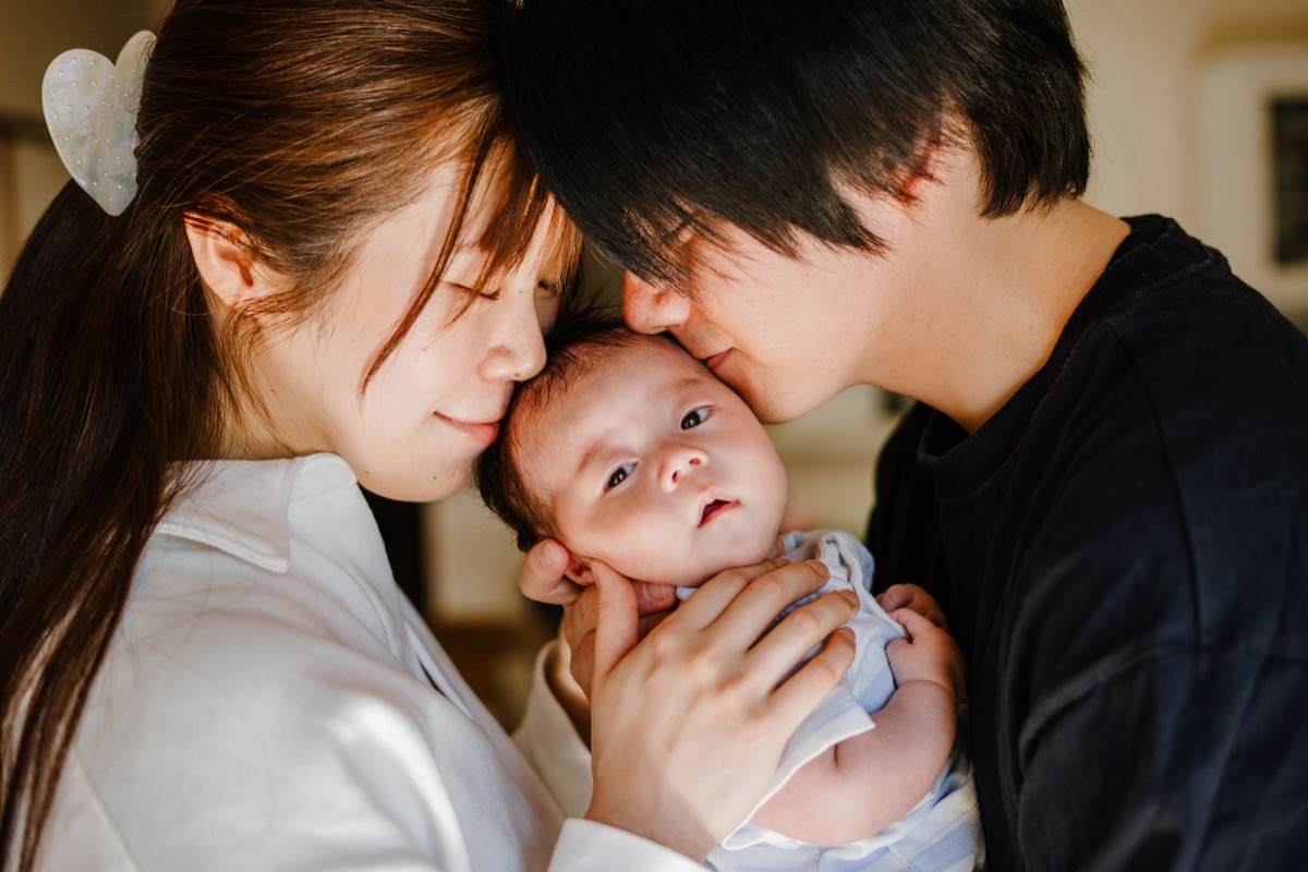 新生児を抱いて寄り添うご夫婦の写真