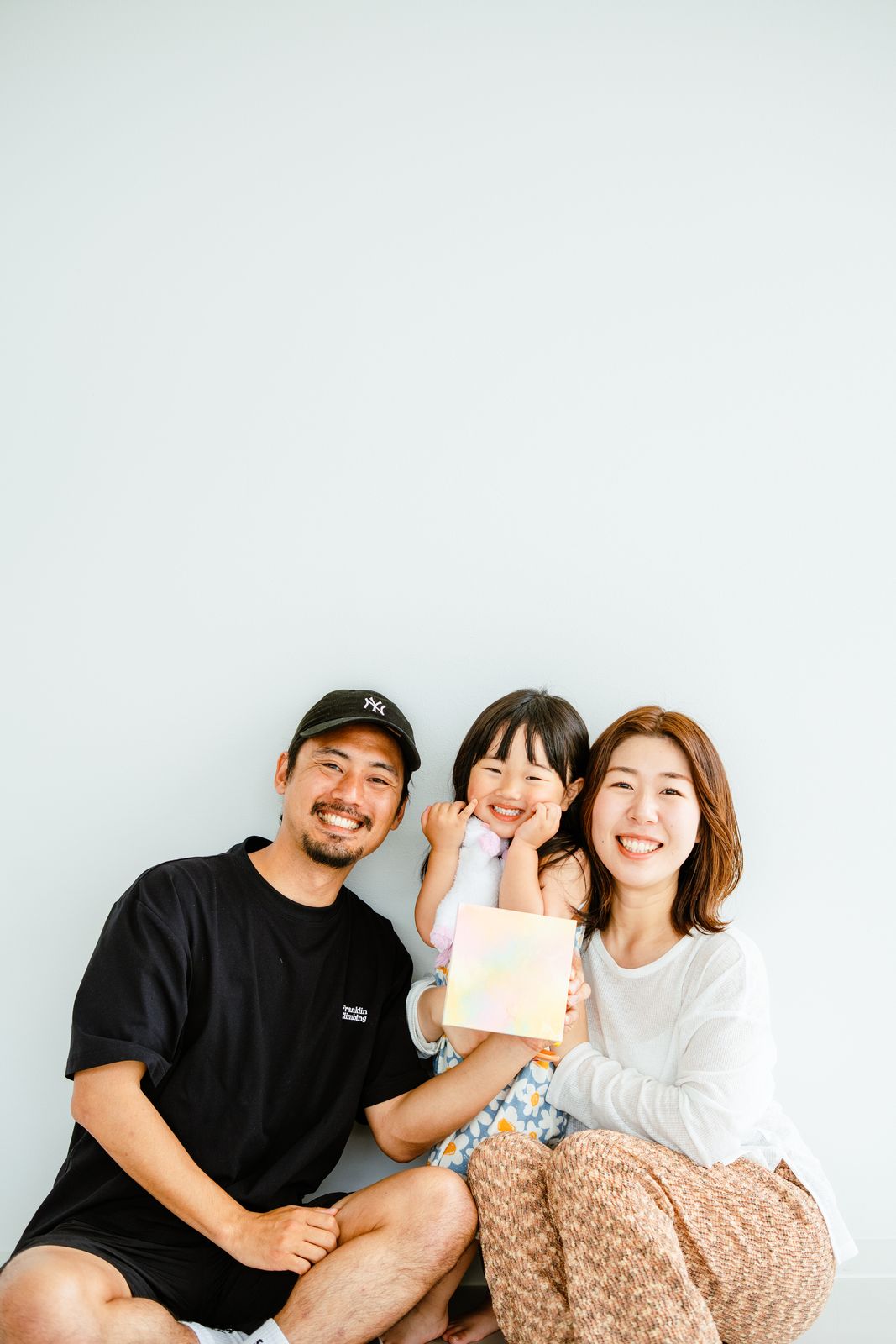 白い背景で笑顔を見せるご家族3人の写真