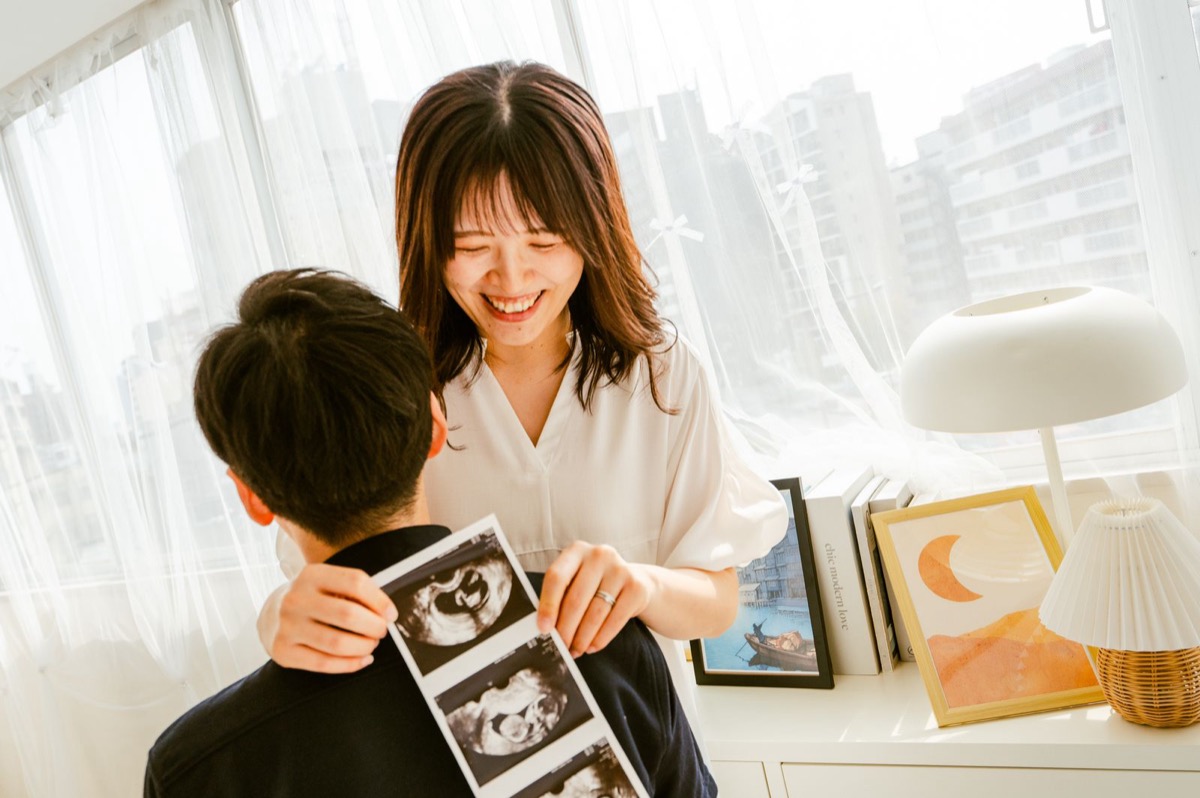エコー写真を見せて笑い合うご夫婦のマタニティ写真