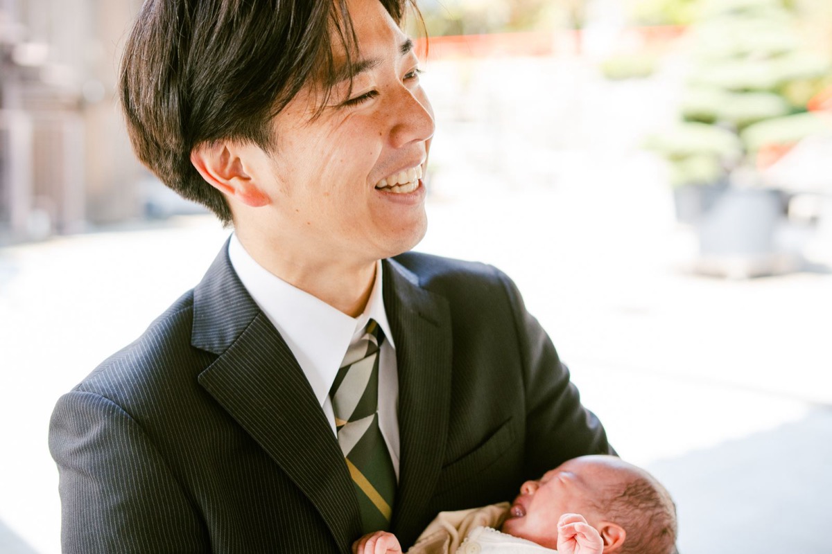 お宮参りで新生児を抱くお父さんの写真