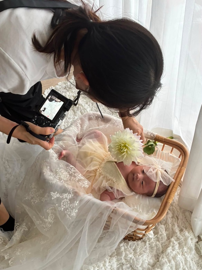 花とベビーバスケットで新生児を撮影するkaede.
