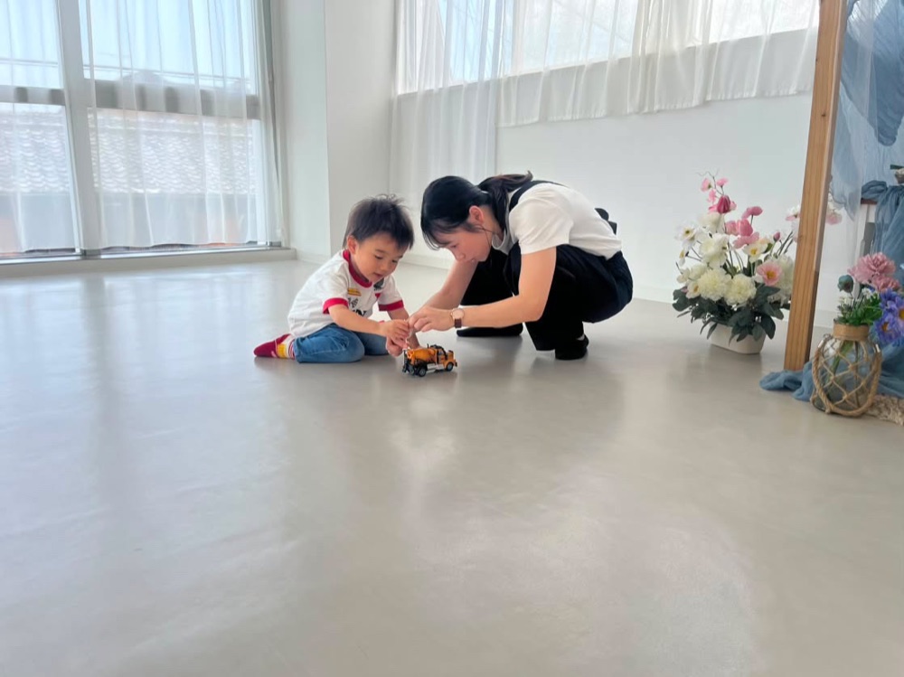花を手に子どもとおもちゃで遊びながら撮影するkaede.
