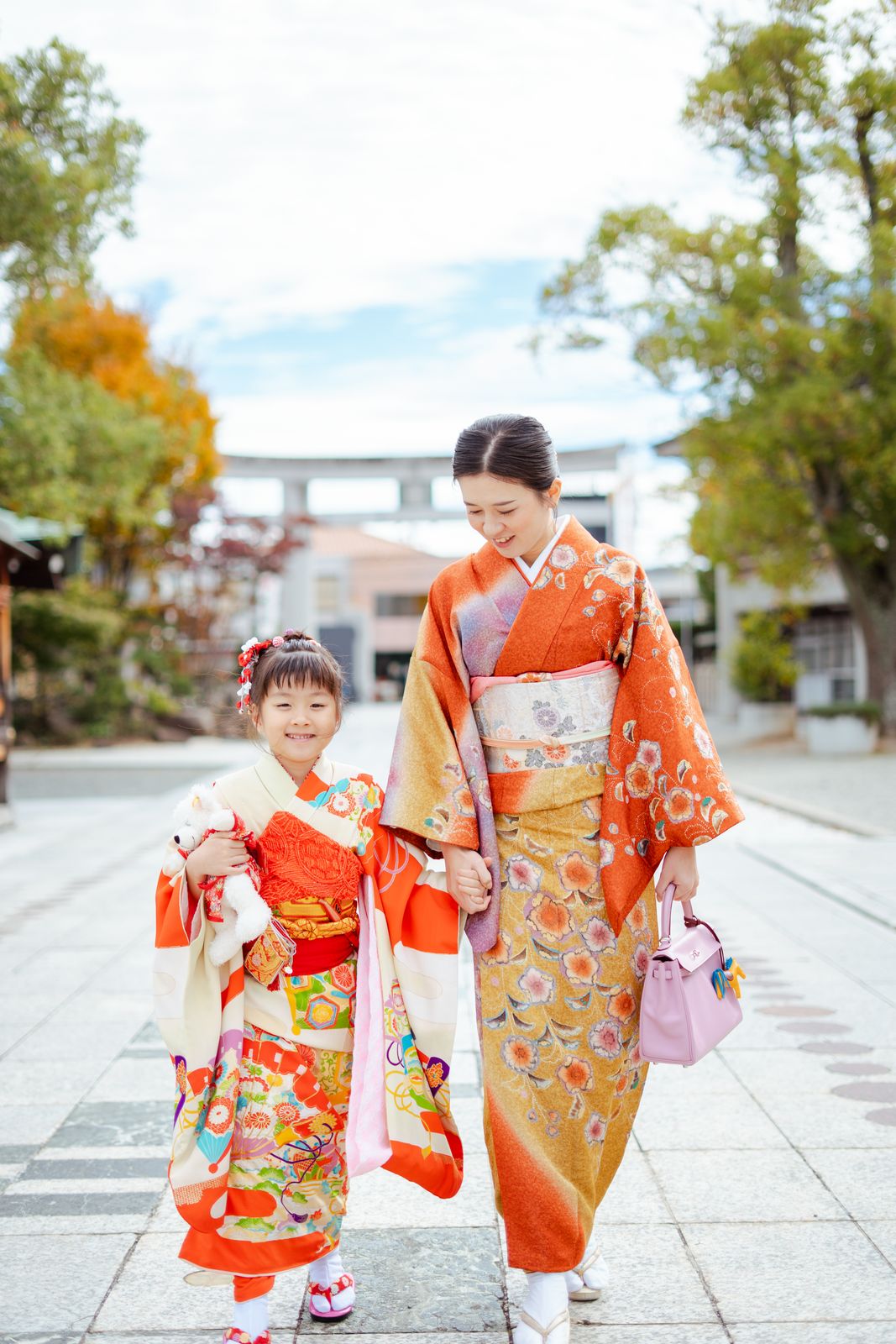 鳥居前を手をつないで歩く七五三の母娘の写真