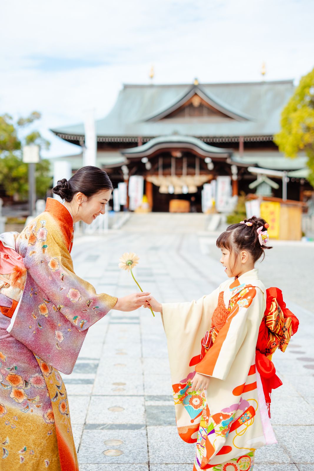 神社で花を手渡す七五三の母娘の写真