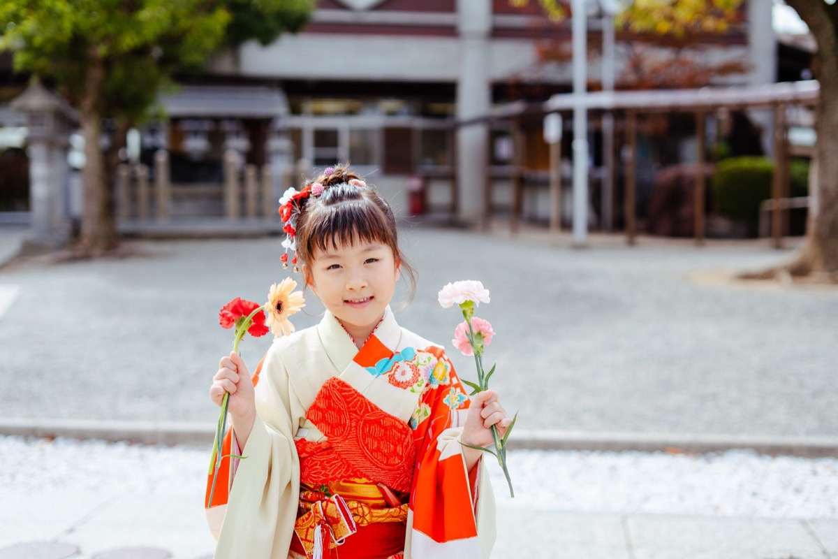 花を持ってほほえむ七五三の女の子の写真